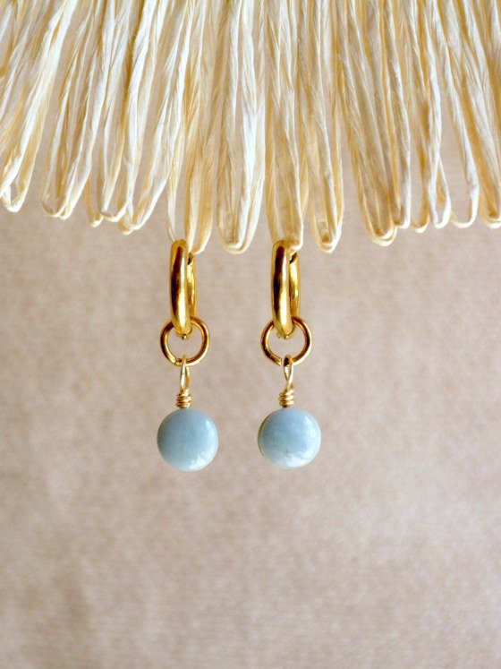 Aretes Belai Jade Pequeño, argollas de acero con pequeño dije de piedra jade verde, apoyados sobre fibra de rafia y lino
