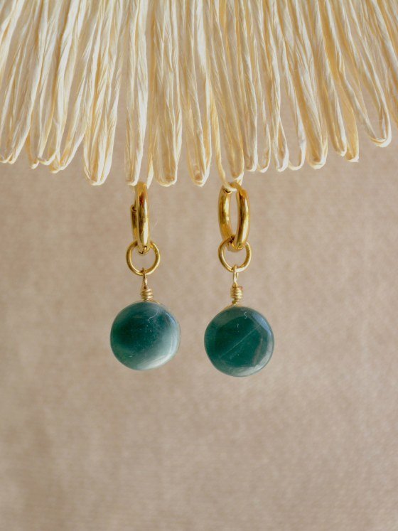 Aretes Belai Jade Princesa Redondo, argollas de acero dorado con dije redondo de piedra jade, apoyados sobre fibra de rafia y lino