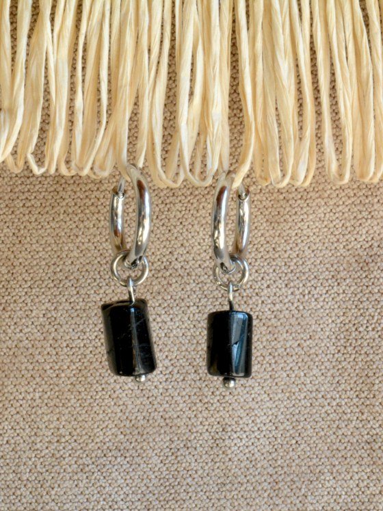 Aretes Belai Turmalina, argollas de acero con dije de turmalina negra, apoyados sobre fibra de rafia y lino