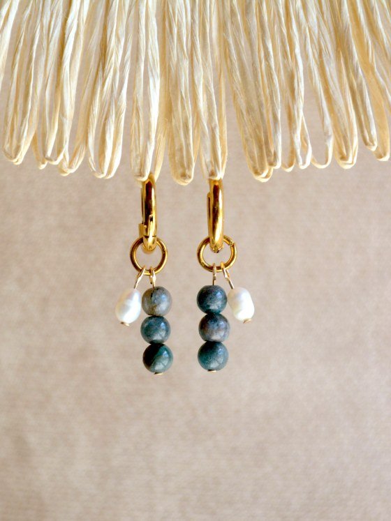 Aretes Belai Trio Apatita y Perla, argollas de acero con racimo de tres cuentas: apatita azul, perla blanca y apatita azul, apoyados sobre fibra de rafia y lino