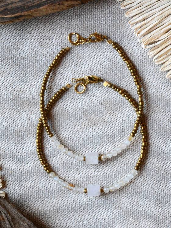 Pulsera Belai Citrino y Cuarzo Dorado, cuentas doradas con citrino facetado y un cuarzo blanco cúbico, apoyada sobre lino junto a madera y fibra natural