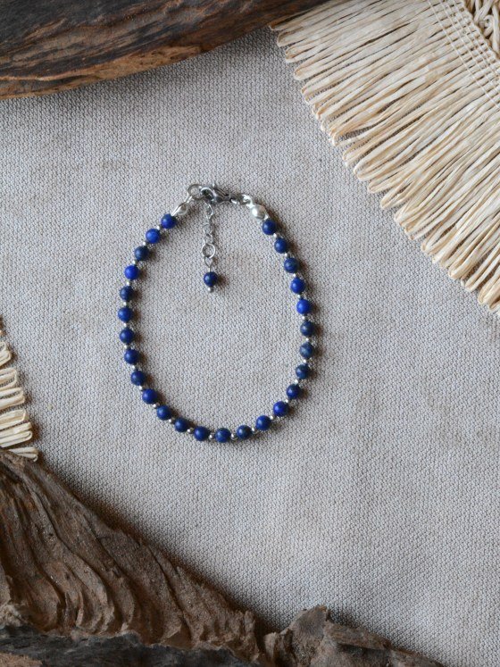 Pulsera Belai Lapislázuli Plateada, cuentas de lapislázuli azul intenso con detalles plateados, apoyada sobre lino junto a madera y fibra natural