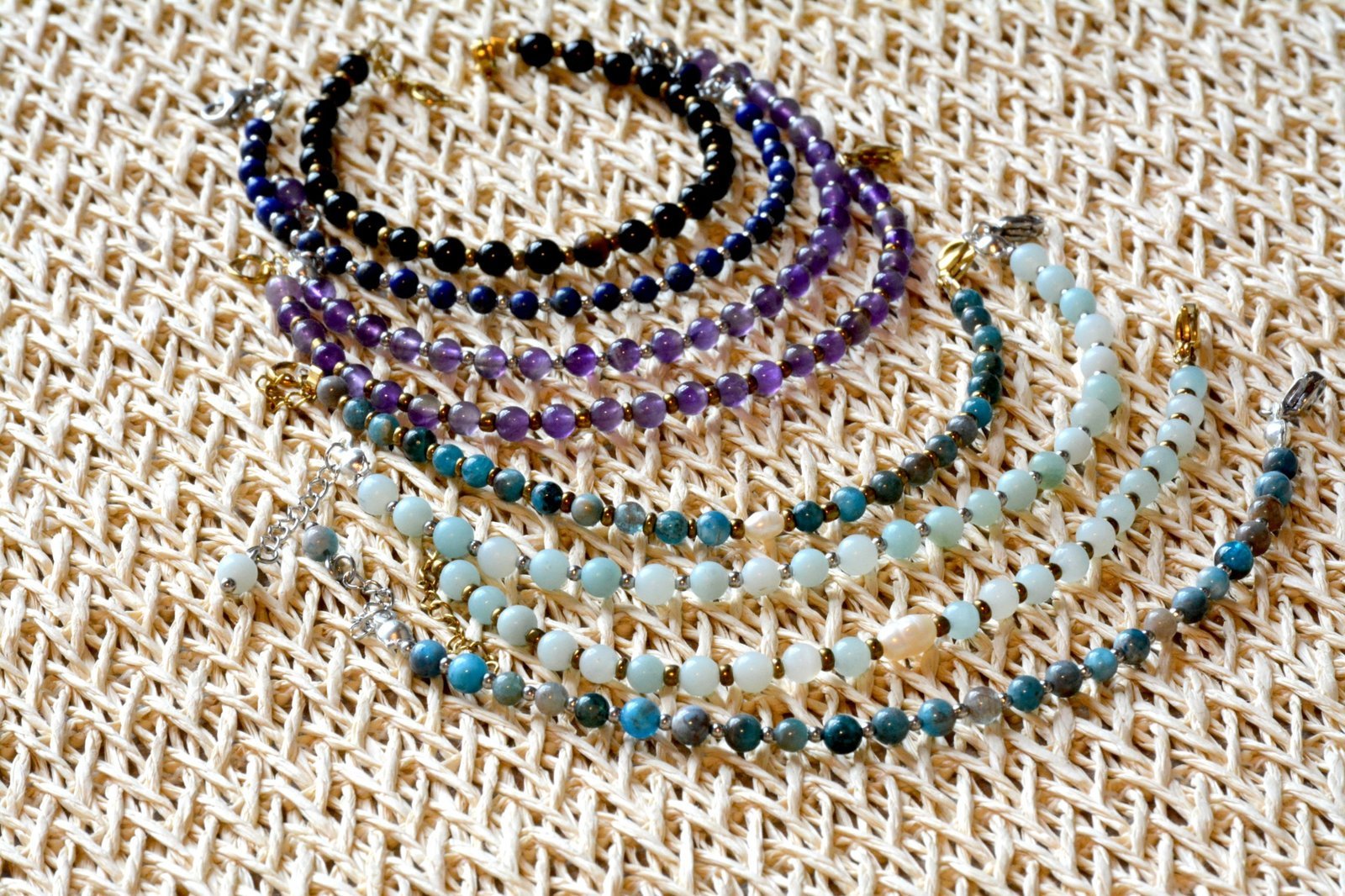 Pulseras Belai de piedras naturales apiladas sobre un tejido de fibra natural: ónix, amatista, lapislázuli, amazonita, apatita y perlas combinadas con separadores dorados y plateados